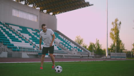 Tilt-up-with-slow-motion-of-male-from-professional-soccer-league-juggling-ball-on-leg-in-outdoor-playing-field-on-sunny-summer-day